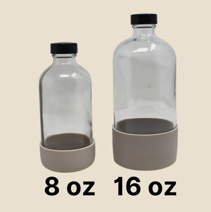 Two glass bottles with black lids and gray bases, labeled 8 oz and 16 oz on a beige background.
