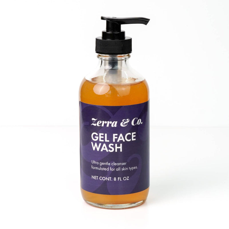 A clear bottle with a black pump, labeled Zerra & Co. Gel Face Wash, contains orange gel face wash ideal for fragrance-free skincare routines.