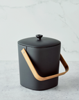 black container with wooden handle and lid on marble background