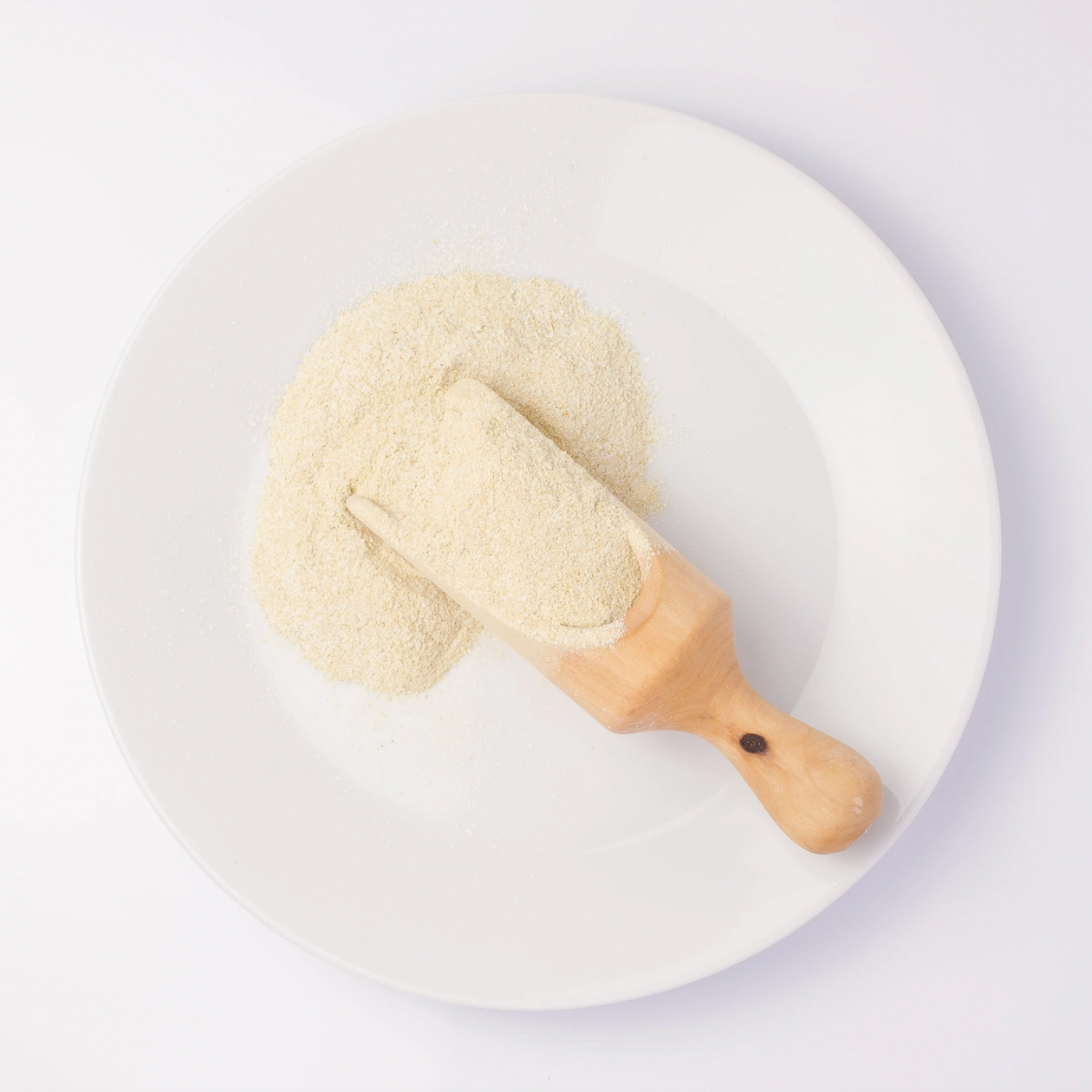 cream colored grains on wooden spoon on white plate