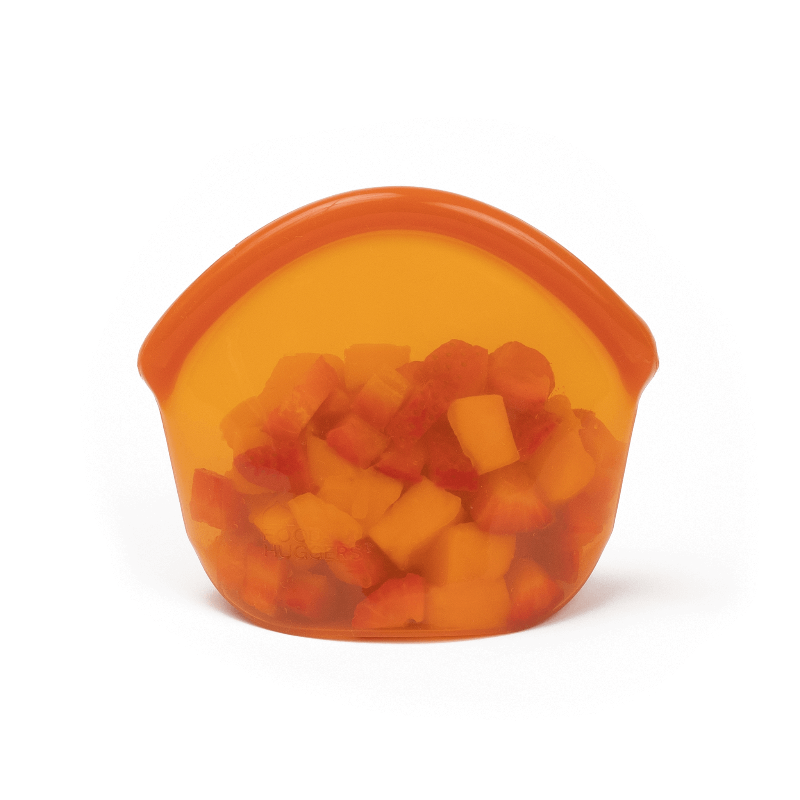 Small Amber Transparent silicone reusable snack bag holding sliced fruit on a white background. 