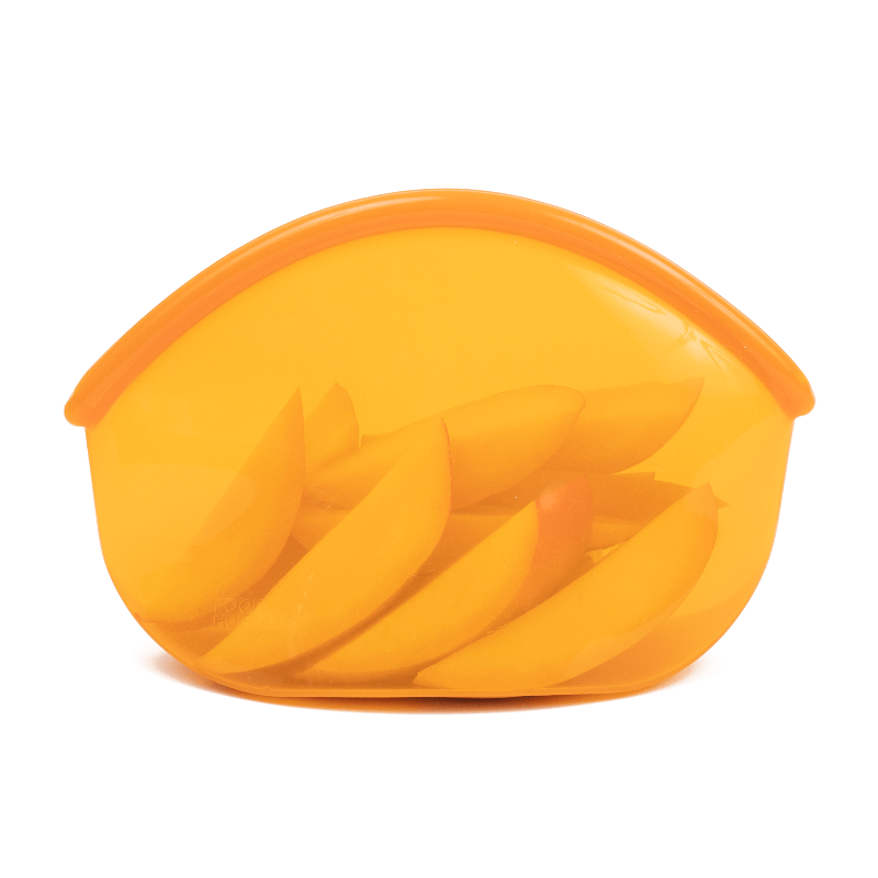 An Amber transparent reusable silicone bag holding sliced apples on a white background