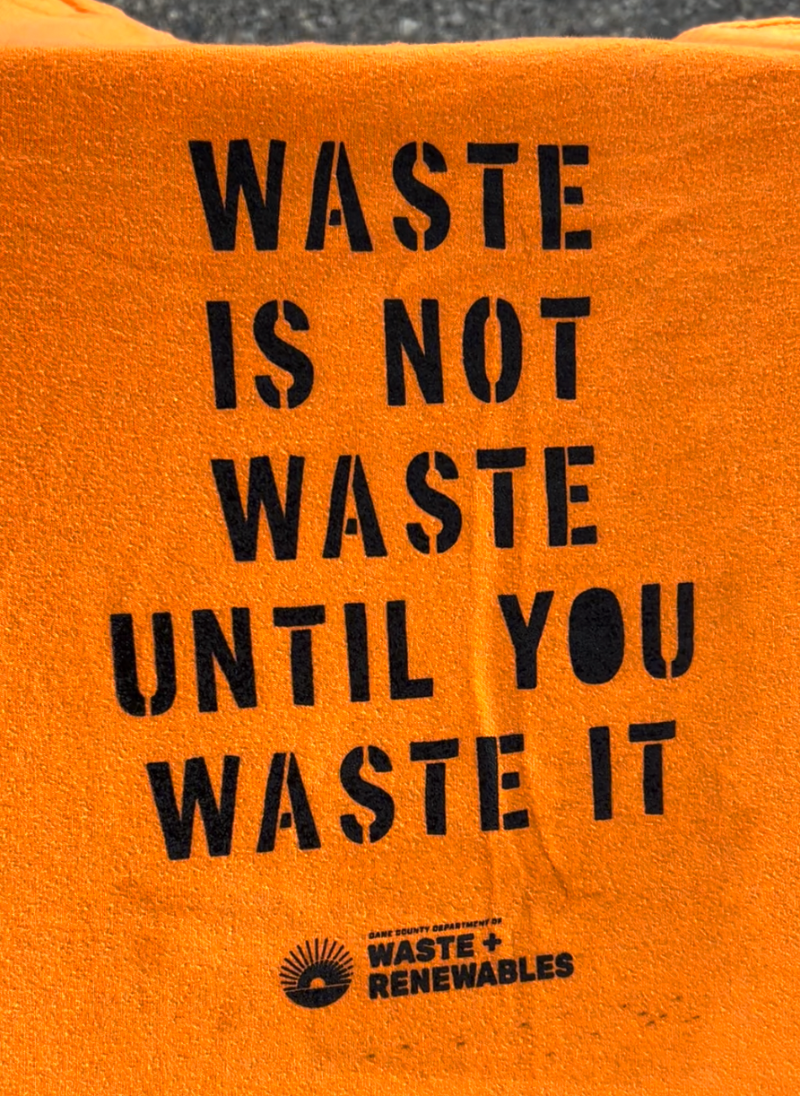 orange tee shirt with "waste is not waste until you waste it" lettering