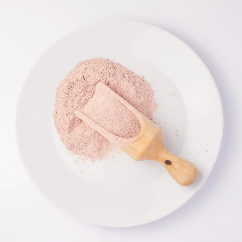 pink grains on wooden spoon on white plate