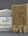 Jangle's Kitchen and Gardener's Soap. The brown bar is stamped with an image of a goat kicking bubbles. Two bars are unwrapped and one is upright on top of the other and the third bar is wrapped in paper. 