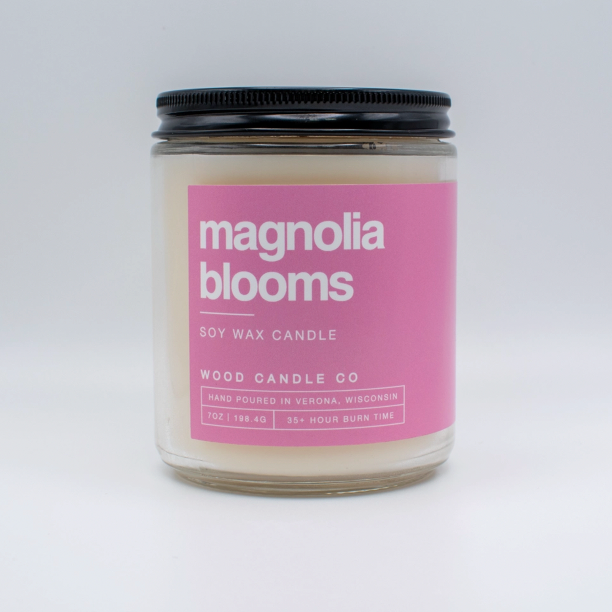 magnolia soy candle jar with pink label on white background