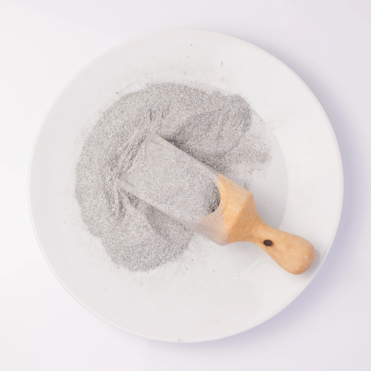 grey grains on wooden spoon on white plate