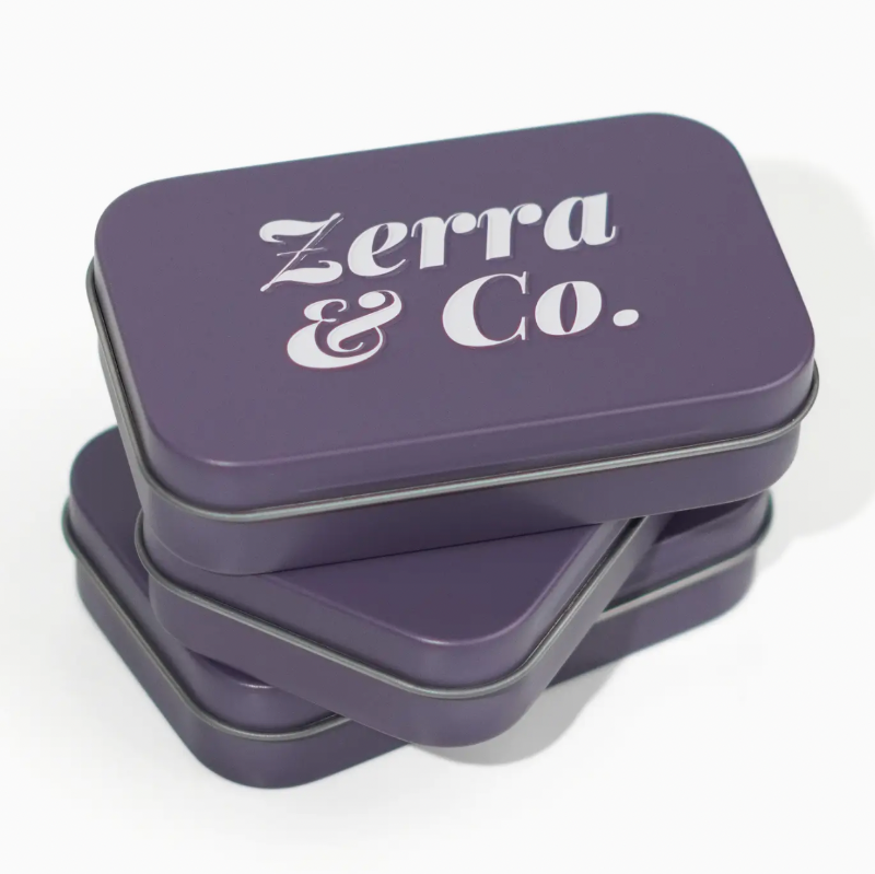 Three stacked square metal tins in a muted purple color, with the top tin displaying the white text 'Zerra & Co.' on its lid, set against a clean white background.