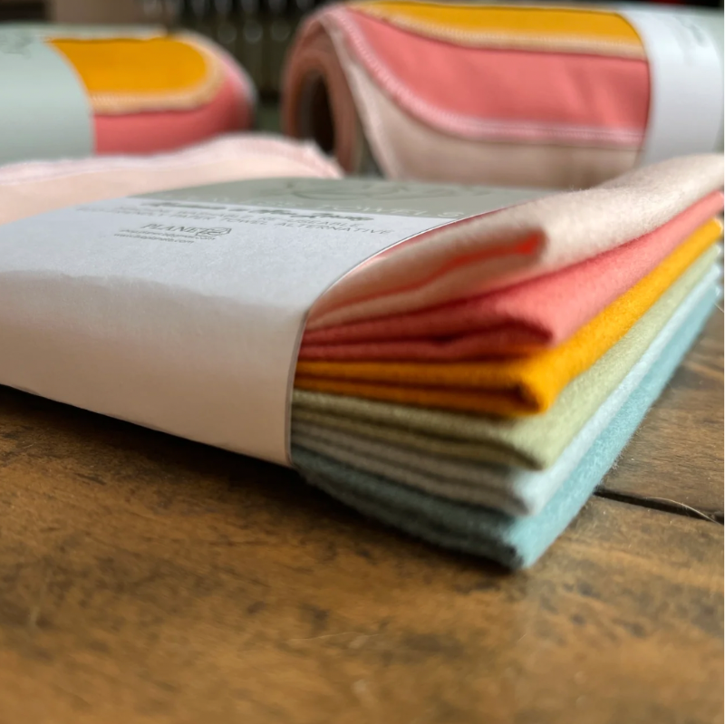 Set of folded colorful fabric swatches on a wooden surface