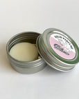 Solid perfume in a metal tin with a decorative label on a white background