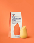 Solid conditioner bar and packaging on an orange background
