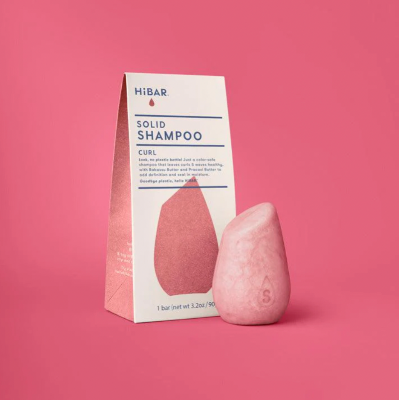 Pink solid shampoo bar with HIBAR packaging on a pink background