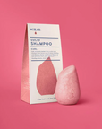 Pink solid shampoo bar with HIBAR packaging on a pink background