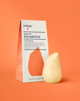 Solid shampoo bar and packaging on an orange background