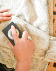 hand rubbing sweater stone on cream sweater