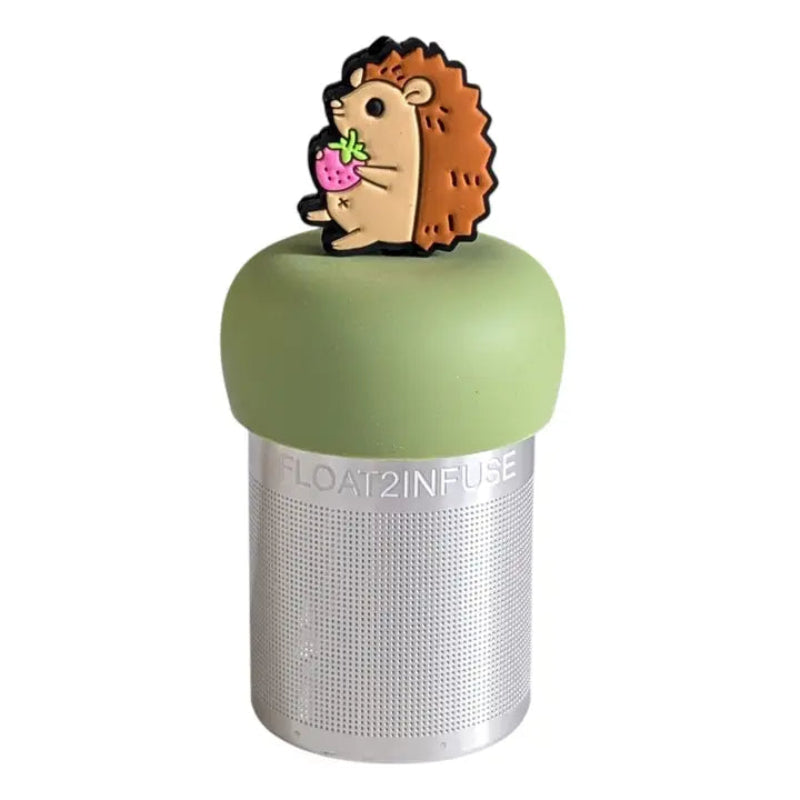 The Teany Tiny Kitchen Floating Tea Infuser features a stainless steel design with a green silicone lid topped by a cute hedgehog holding a strawberry, making tea steeping fun and enjoyable.