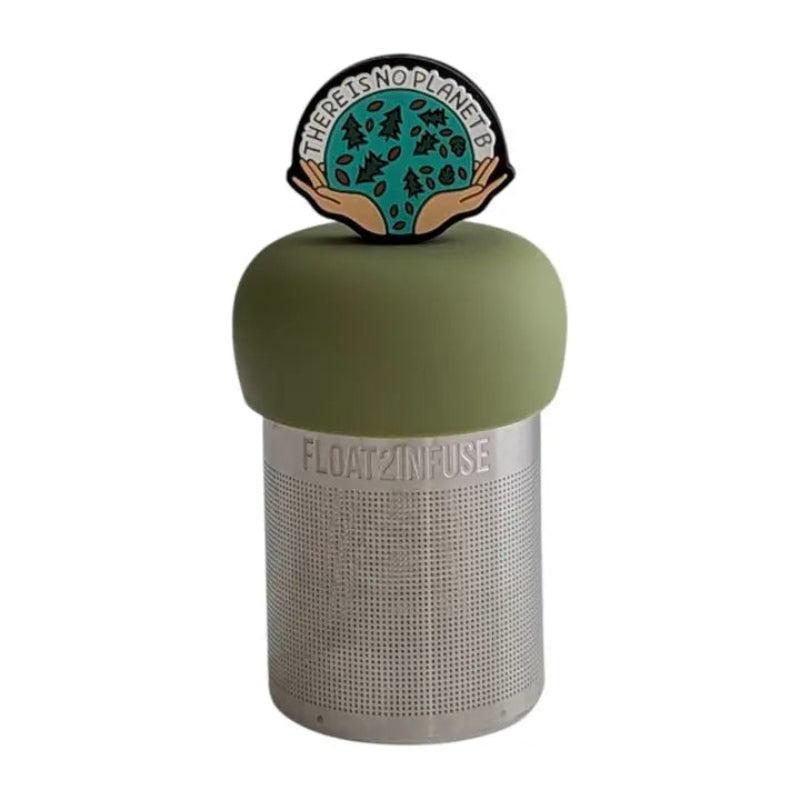The Teany Tiny Kitchen Floating Tea Infuser features a stainless steel design with a green silicone lid topped by a hands holding a circle full of trees and seeds arcing between the hands is text reading "there is no Planet B"