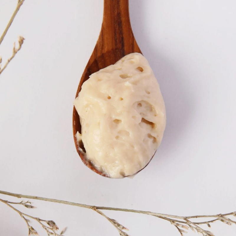 wooden spoon with white cream acne serum in it. 