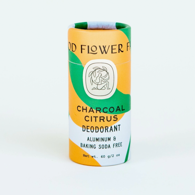A cylindrical Good Flower Farm Deodorant Stick with an orange, green, and white abstract design; label notes it’s aluminum- and baking soda-free. Net weight: 60g/2oz.