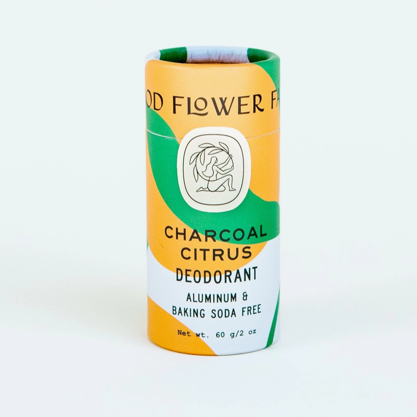 paper tube of charcoal citrus deodorant orange and green stripped tube on white background