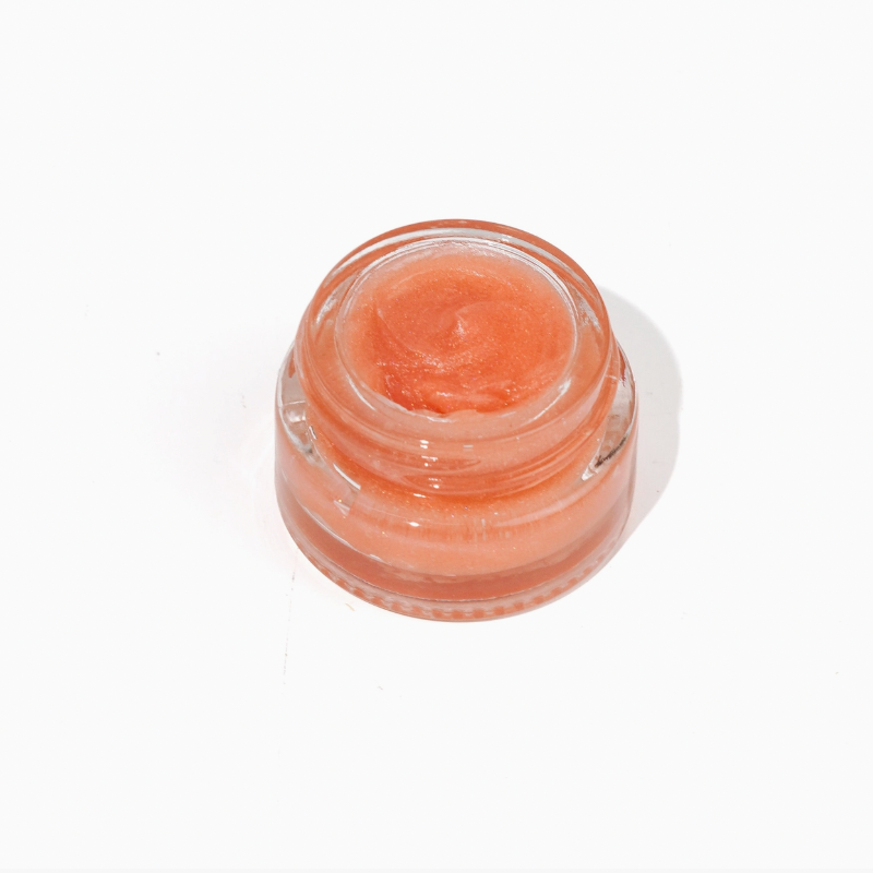 glass jar of light pink lip balm on white background. 