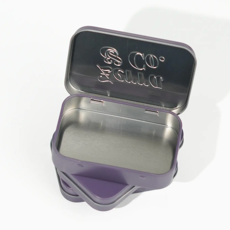 A small open metal tin with a purple exterior and a brushed silver interior. The inside lid is embossed with the brand name 'S.