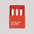 Axiology’s Balmie Sets come in a red, zero-waste box and include three multitasking balm sticks in nude, pink, and red shades—each crayon wrapped in white paper with red text.