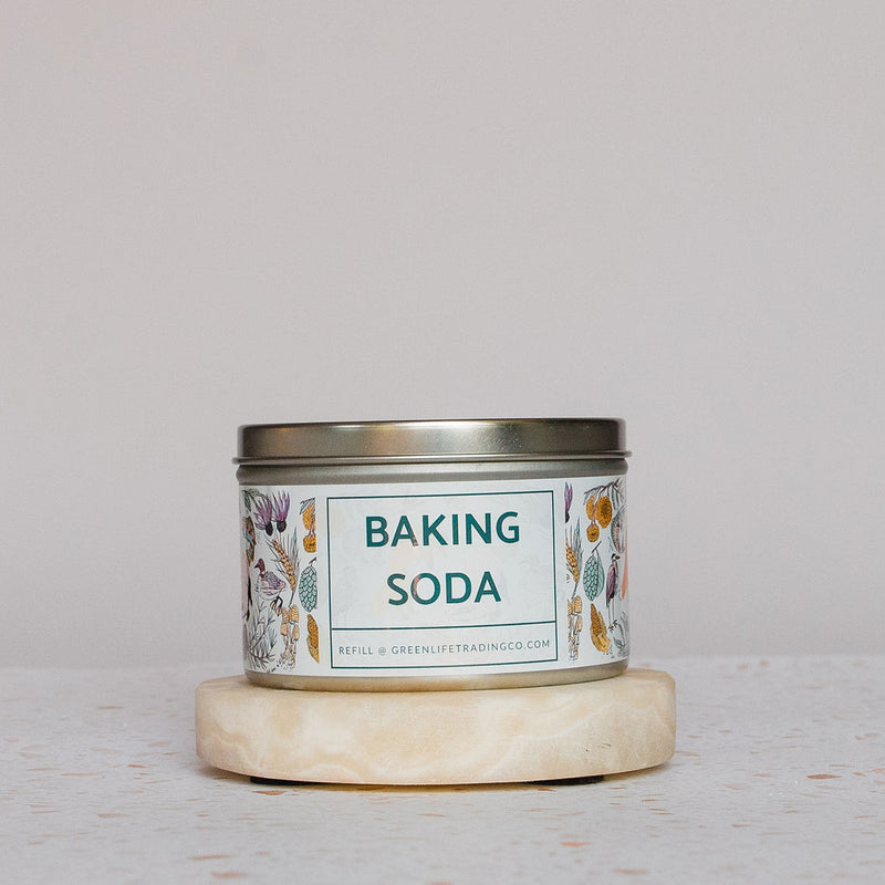 A metal tin of Green Life Trading Co. Baking Soda (Sodium Bicarbonate) with floral designs rests on a round stone coaster against a neutral background.
