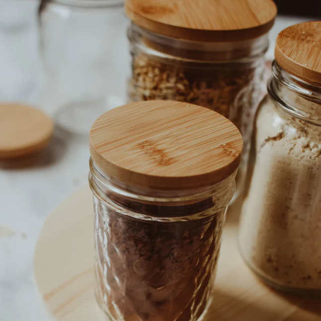 A picture of several reused mason jars with bamboo lids on them. 